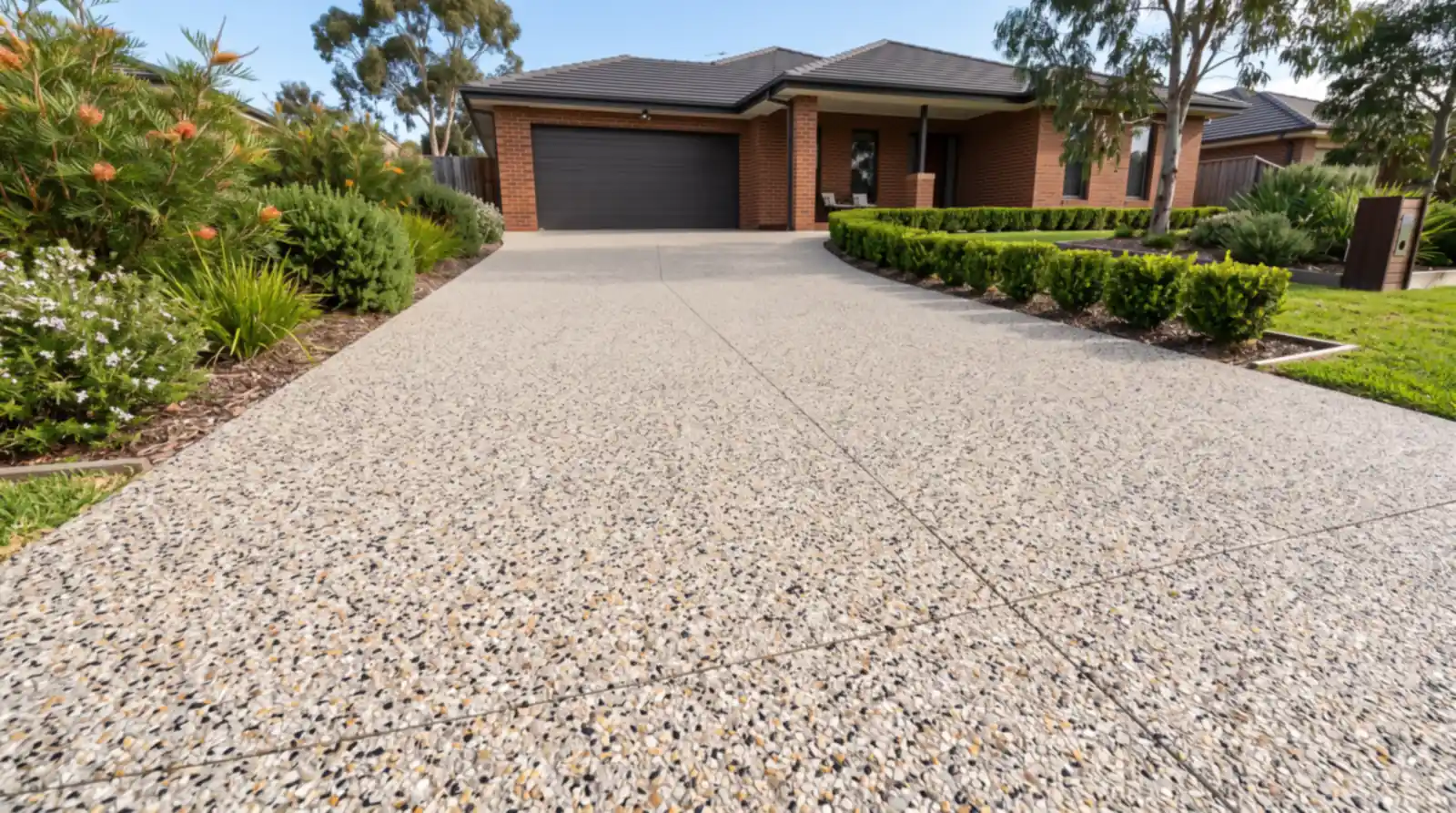 A sealed exposed aggregate driveway with cream, gold and black stone at a brick home in Launceston