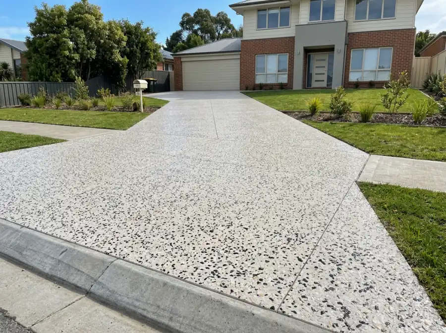 A new pale exposed aggregate double driveway with black and white stone leading to a Launceston home